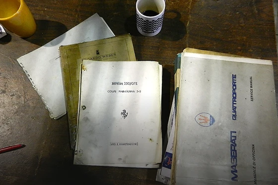 Vintage car manuals and coffee cup on table.